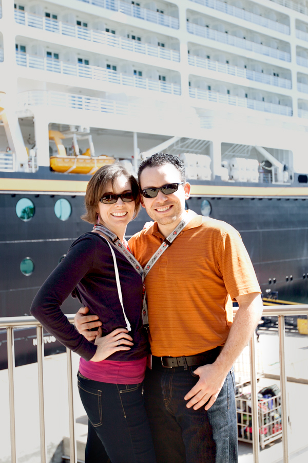 husband and wife in front of a disney ship