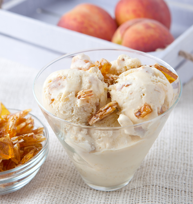 This homemade ice cream is SUMMER in a bowl!! Fresh peaches cooked and pureed with honey are blended into a smooth vanilla base with homemade crunchy almond praline pieces.
