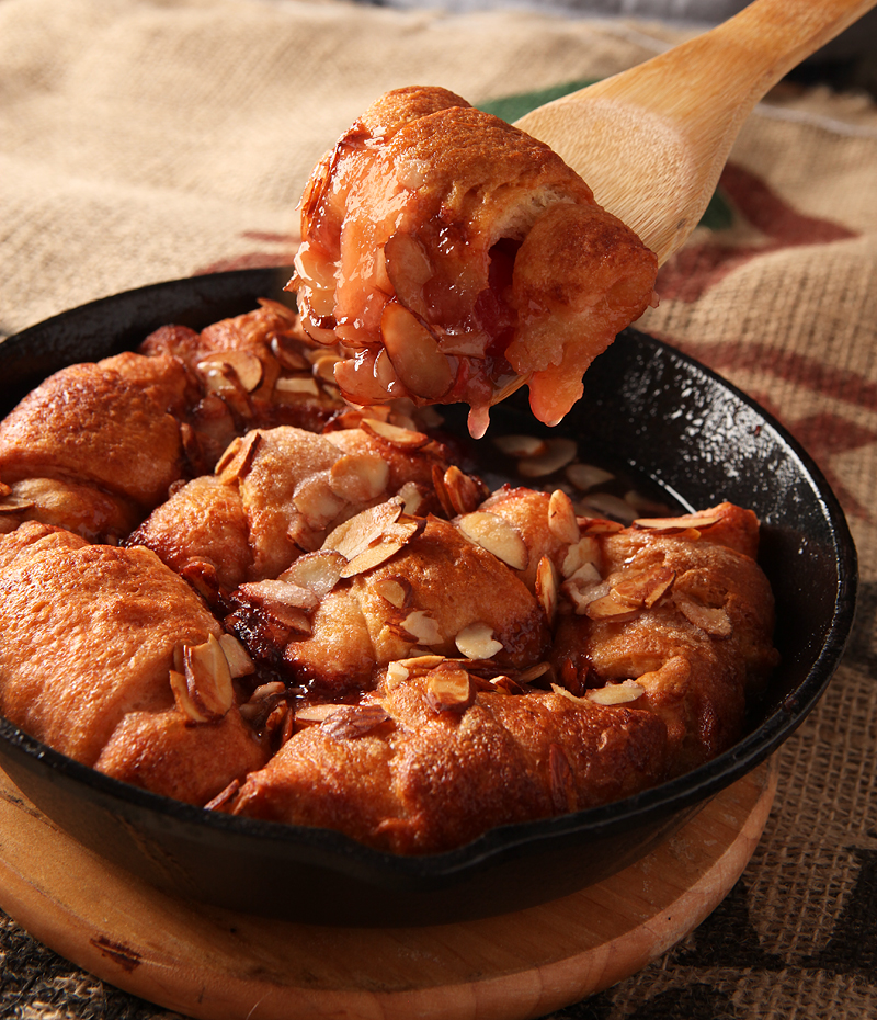 Hot crescent dumplings filled with cherries and covered in a sweet cola glaze and sliced almonds.