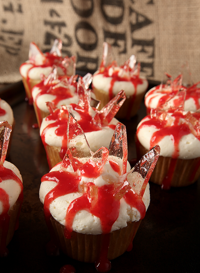 Bleeding broken glass cupcakes for Halloween! Fluffy almond cupcakes filled with cherry pie filling, topped with almond buttercream and finished with cooked sugar "broken glass" and oozing blood (more cherry!)