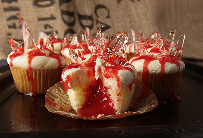 Bleeding broken glass cupcakes for Halloween! Fluffy almond cupcakes filled with cherry pie filling, topped with almond buttercream and finished with cooked sugar "broken glass" and oozing blood (more cherry!)