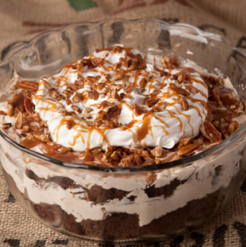 Chocolate turtle trifle - layers of chocolate cake, homemade caramel mousse, pecans, caramel drizzle, and whipped cream make this one amazing dessert that feeds a crowd!