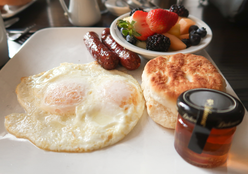 Eggs with a biscuit, sausage links, and fresh fruit at Aviles Restaurant in St. Augustine