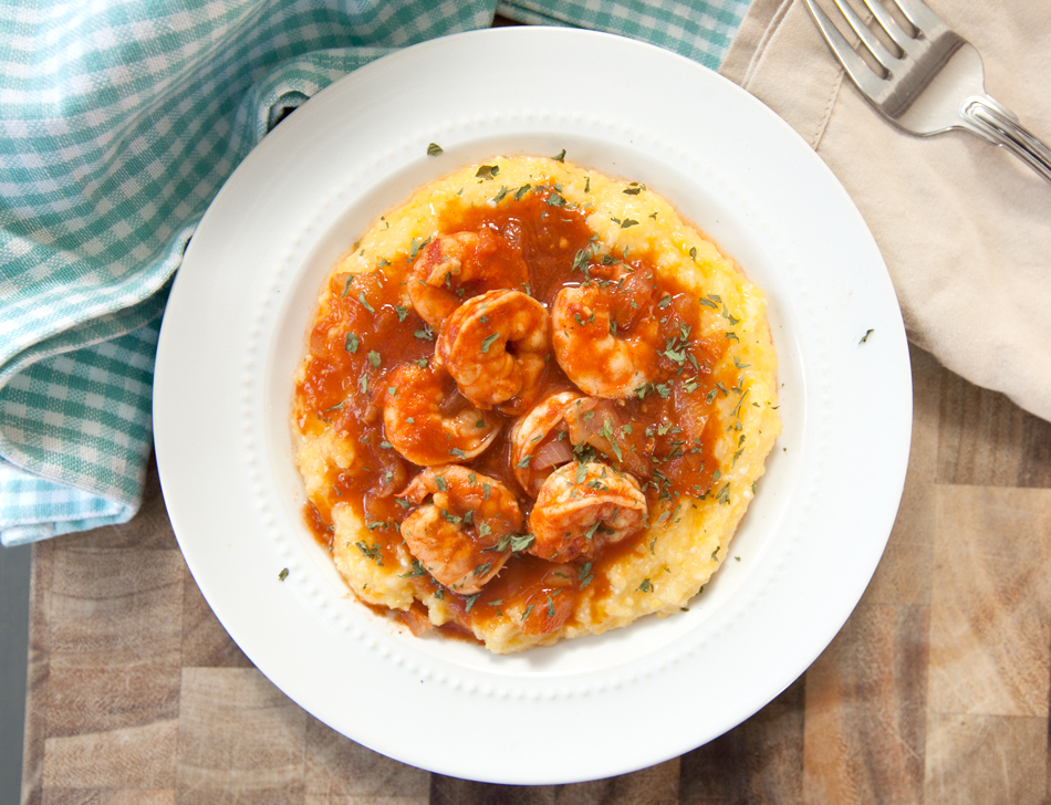 Overhead view of bloody mary shrimp and grits spooned over a generous serving of yellow grits.