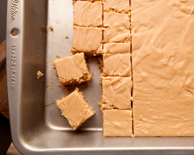 Overhead view of a pan of peanut butter fudge being cut into squares.