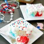 a piece of red white and blue poke cake with bite taken out