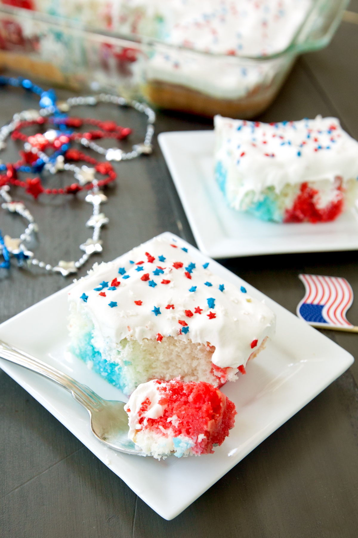 a piece of red white and blue poke cake with bite taken out