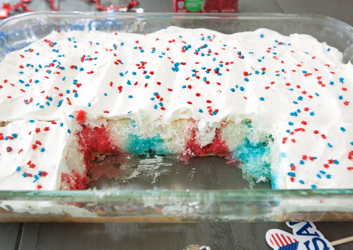 overhead of a red white and blue poke cake with slices cut out