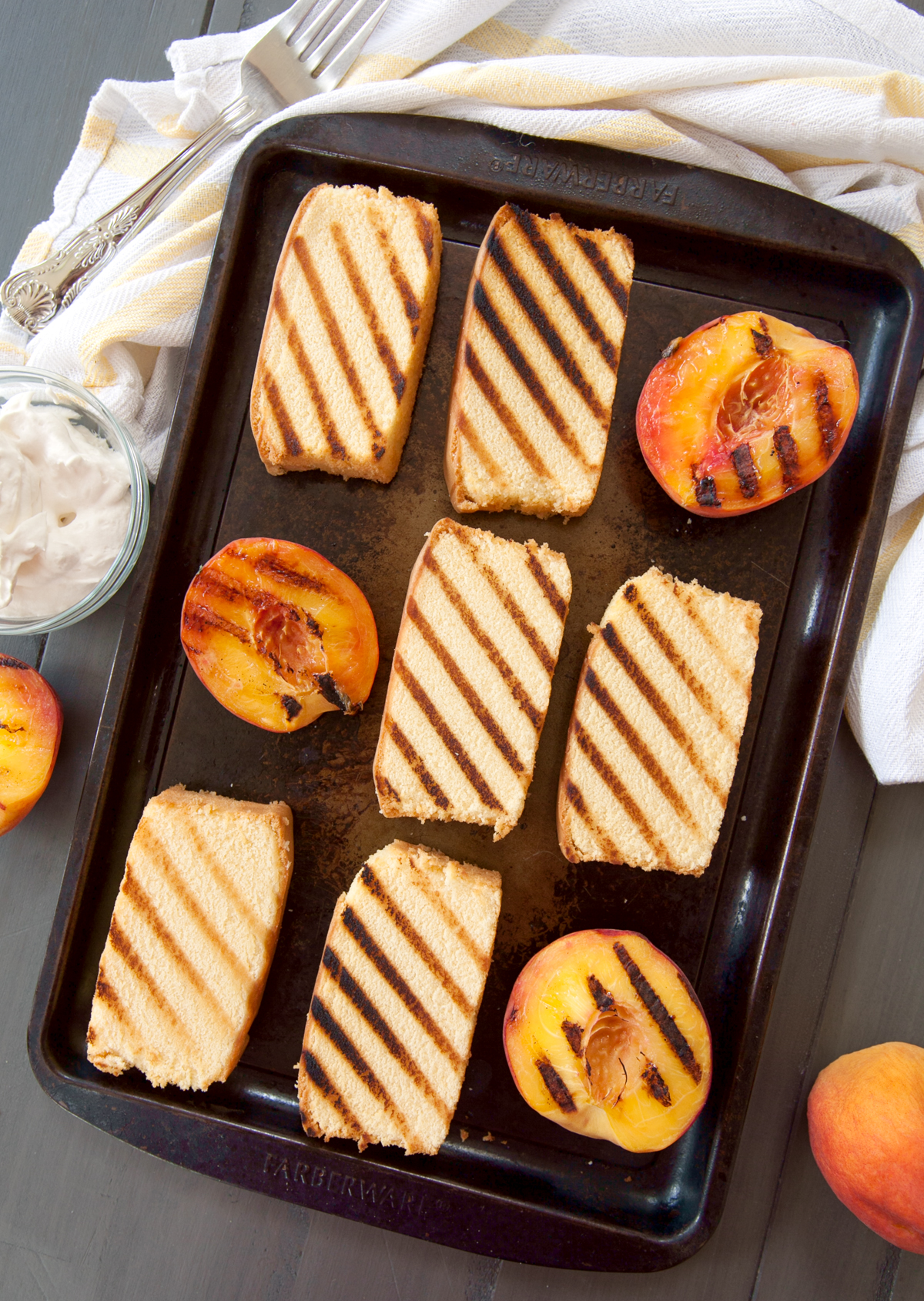 overhead photo of a baking tray full of slices of grilled pound cake and peaches.