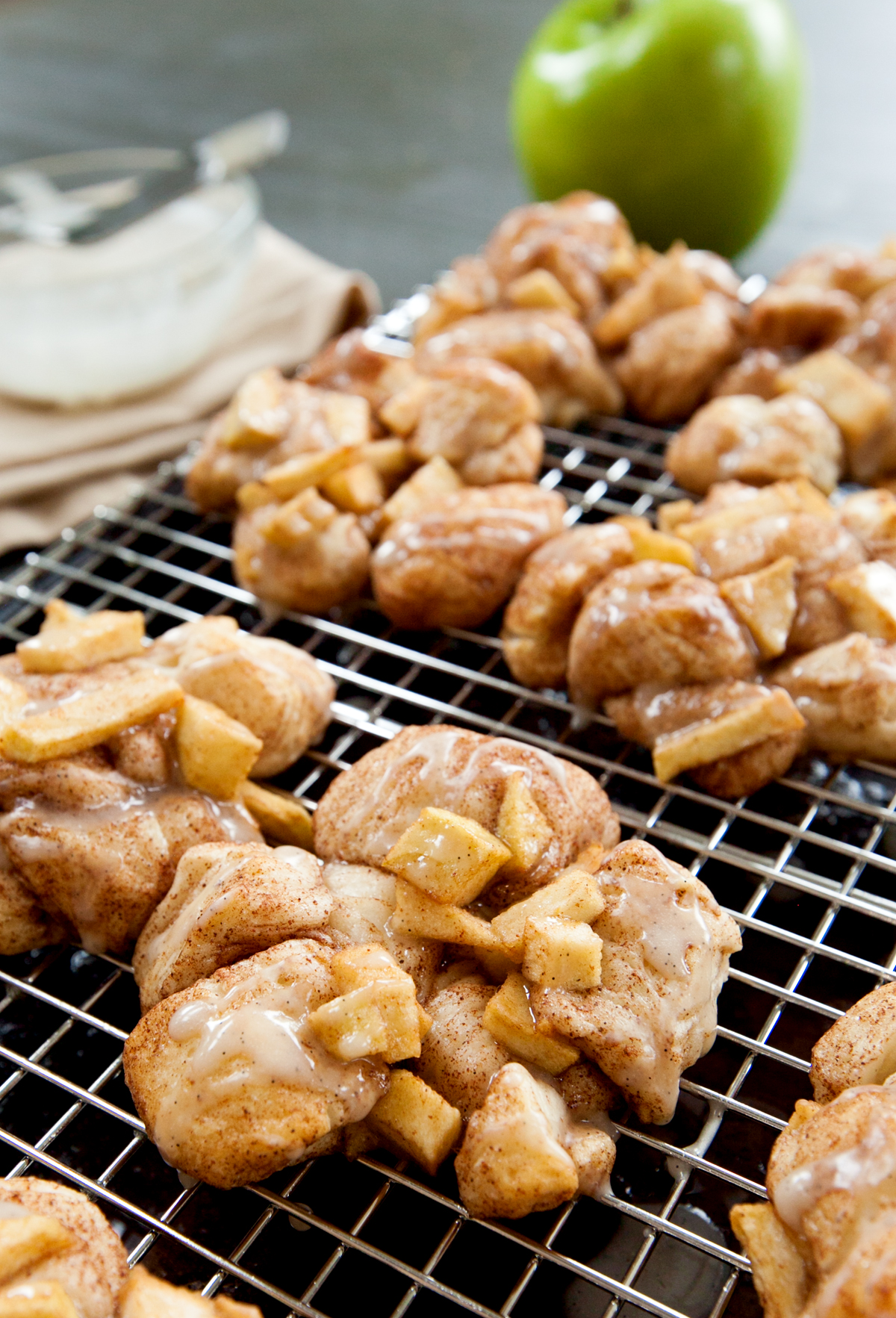 Close up of a baked apple fritter with cinnamon apples and drizzled with glaze.