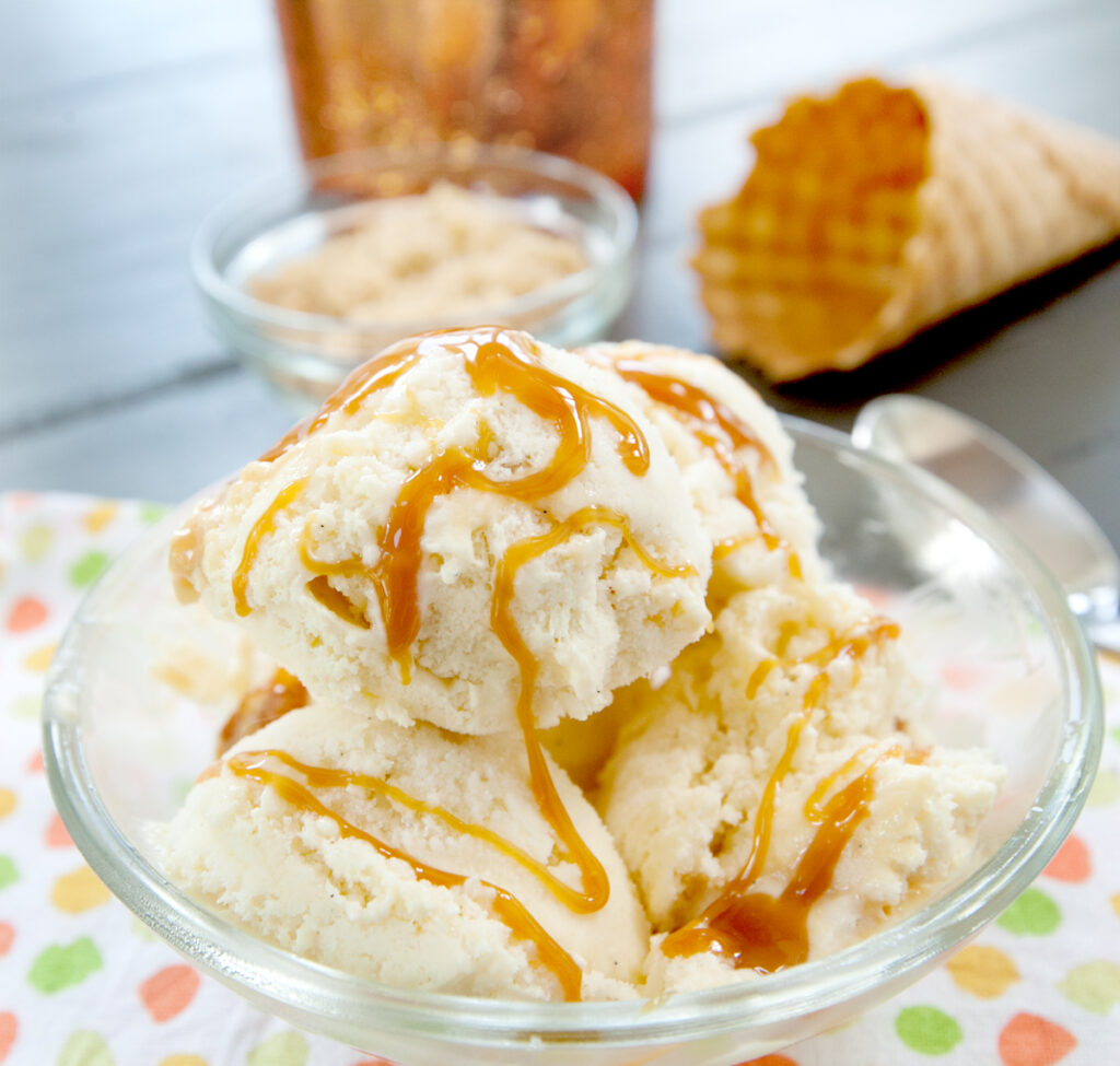 a bowl of several scoops of caramel apple ice cream drizzled with caramel