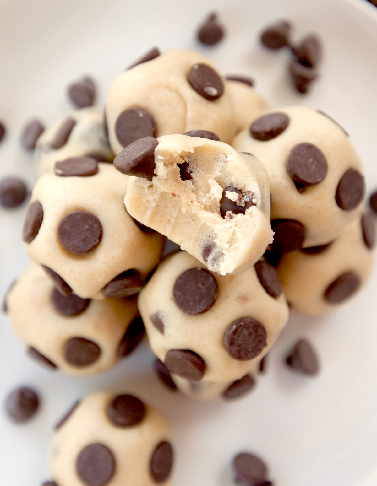 A pile of edible cookie dough bites with a bite taken out of the one on top