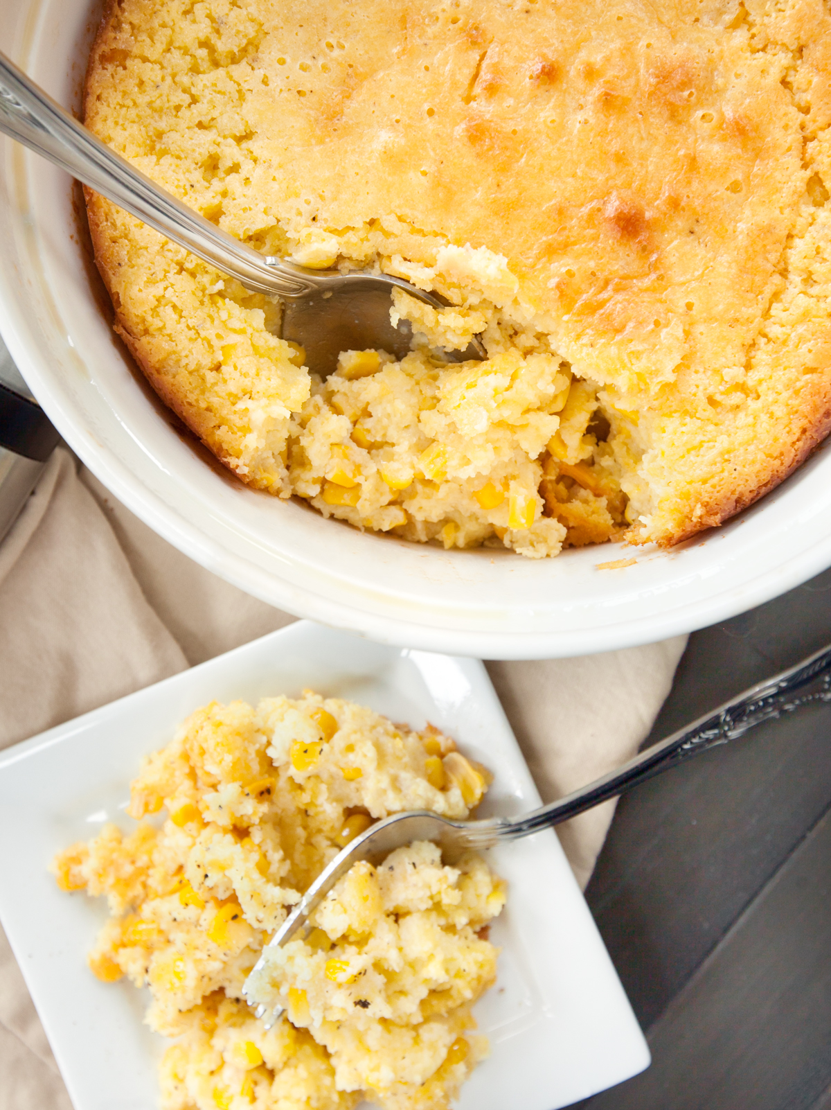 an overhead view of cornbread casserole spooned out onto a plate, with the baking dish also visible