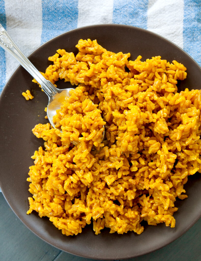 an overhead view of a bed of turmeric rice with a spoon tucked inside