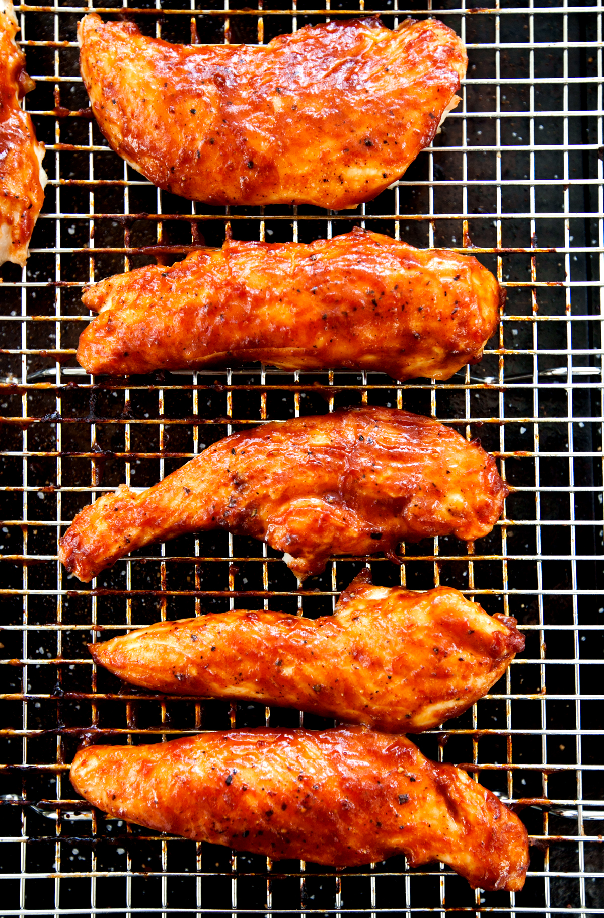 Overhead view of caramelized baked BBQ chicken tenders with barbecue sauce glistening on top