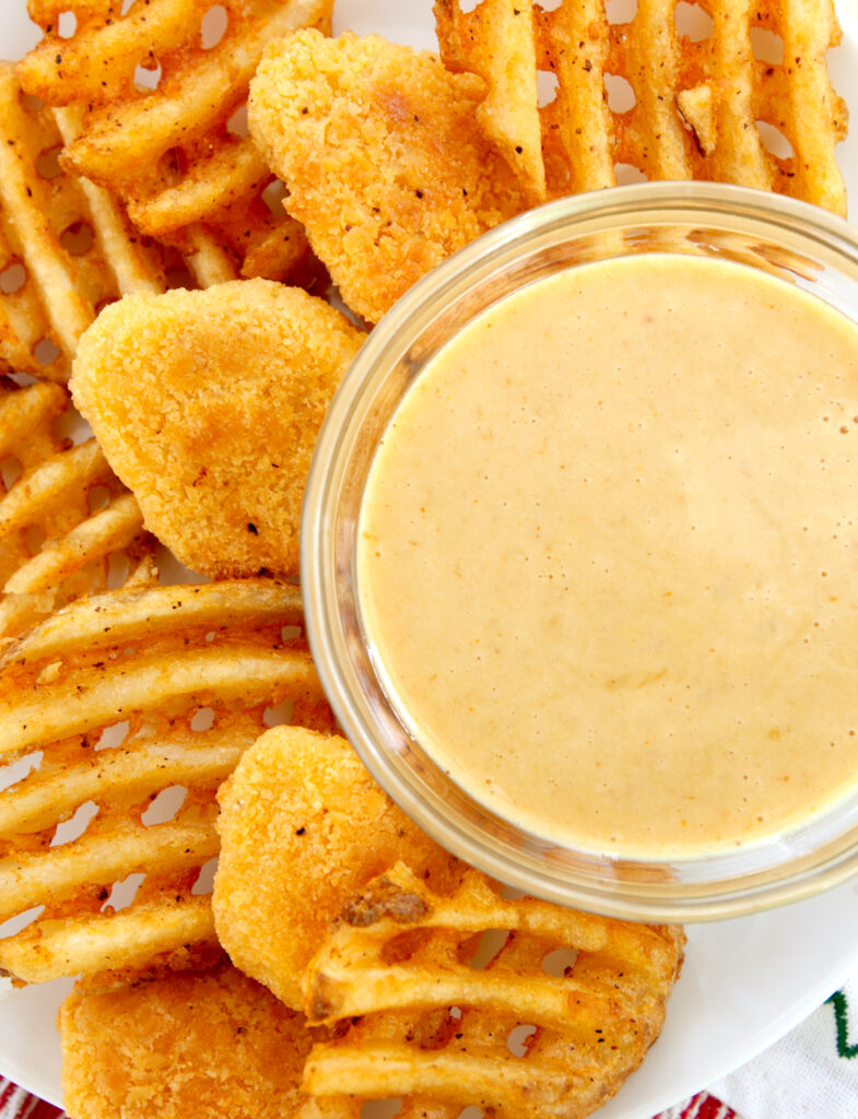 an overhead view of a chick fil a sauce recipe alongside chicken nuggets and waffle fries