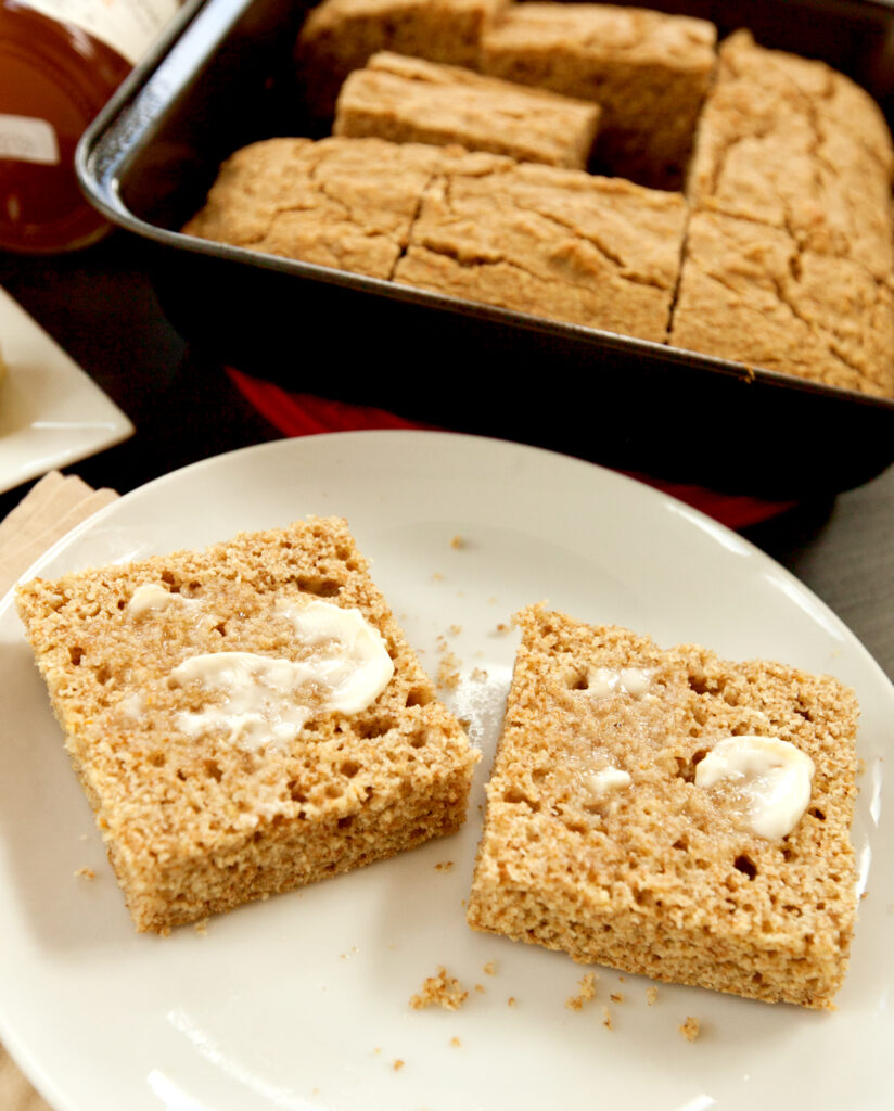 Two slices of healthy cornbread smeared with a bit of melty butter.