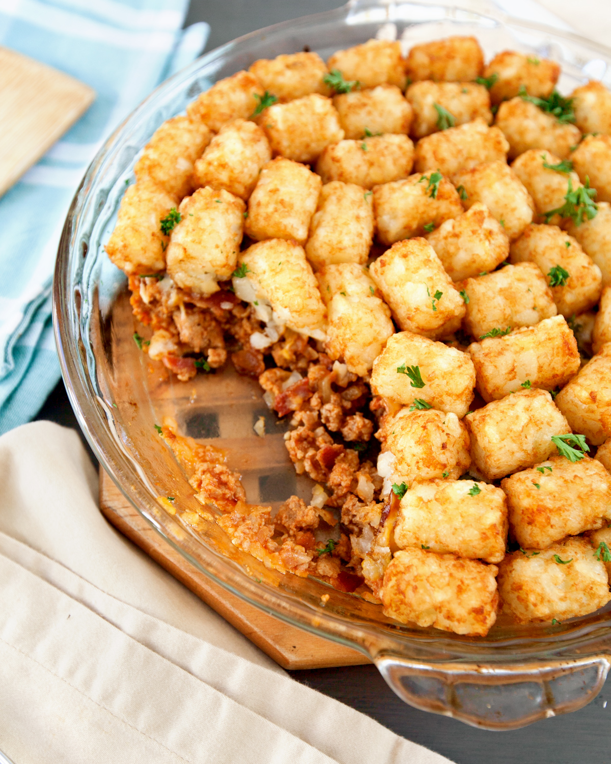 a dish of bacon cheeseburger casserole with tater tots with a serving scooped out