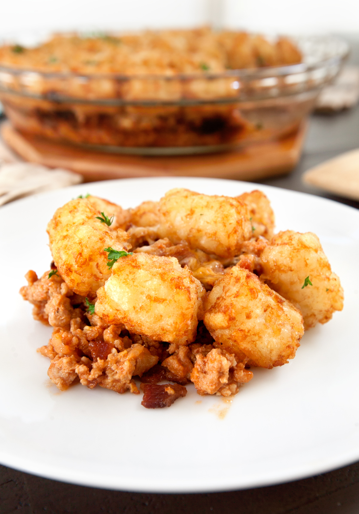 Up close photo of a serving of bacon cheeseburger casserole with tater tots with beef and bacon visible