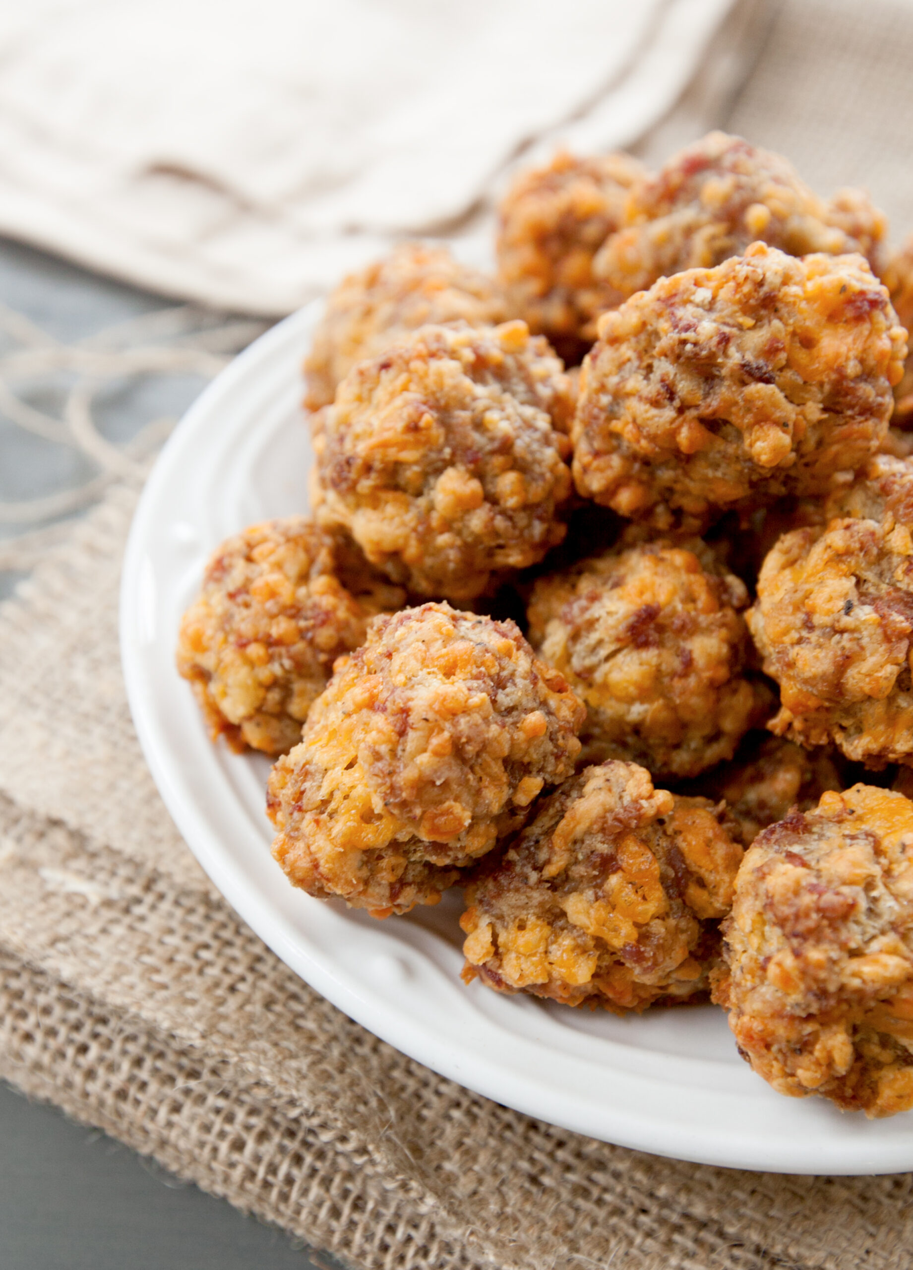 up close photo of a plate of sausage balls without bisquick with lots of sharp cheddar visible.