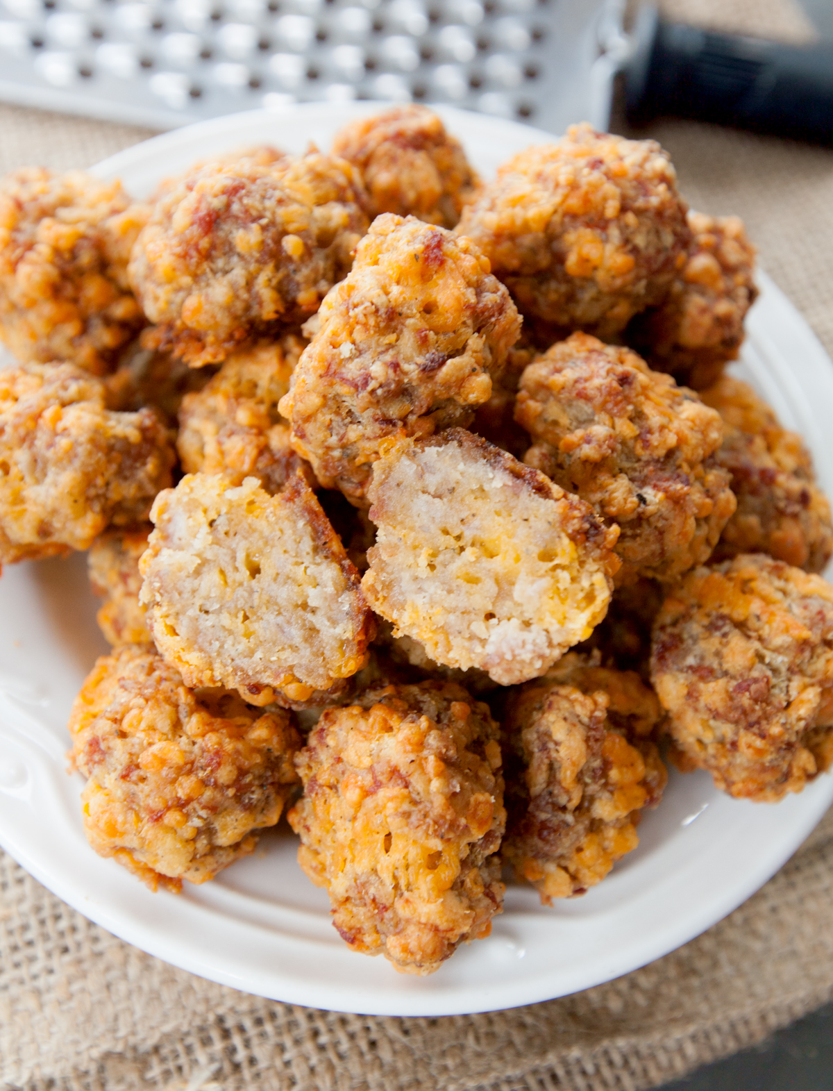 a plate of sausage balls without Bisquick with one cut in half so that the middle is visible.