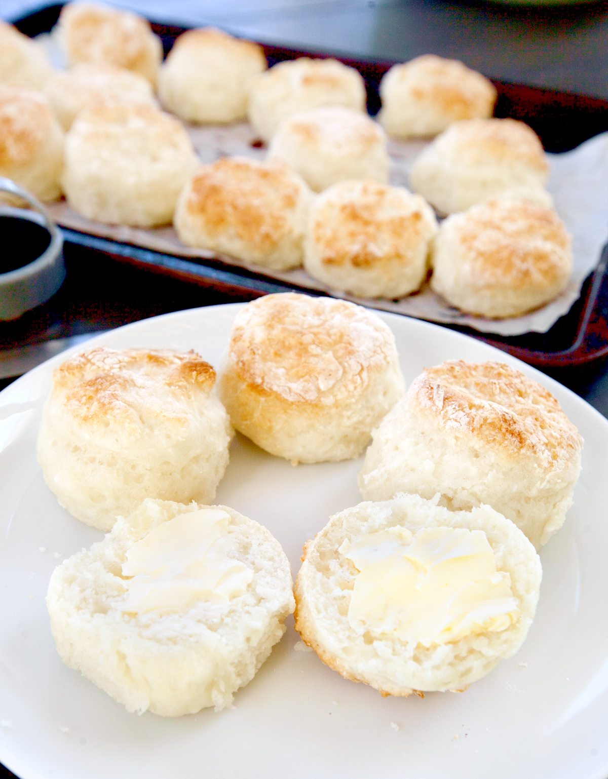 A plate of low calorie biscuits, sliced open on a plate and spread with butter.