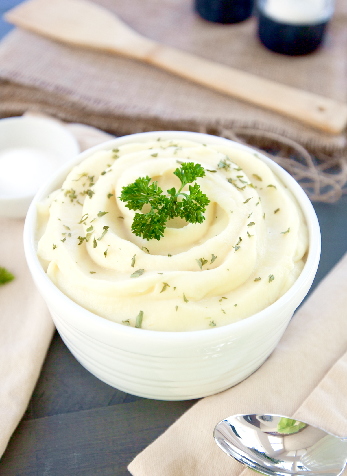 A serving dish of smooth parsnip puree sprinkled with parsley.