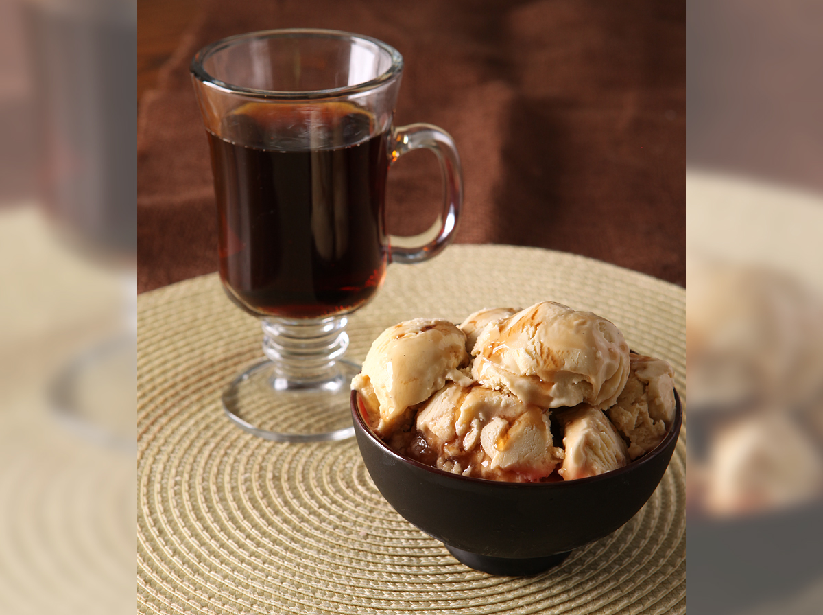 A bowl piled high with the results of a buttercream ice cream recipe with a tall glass of butterbeer in the background.