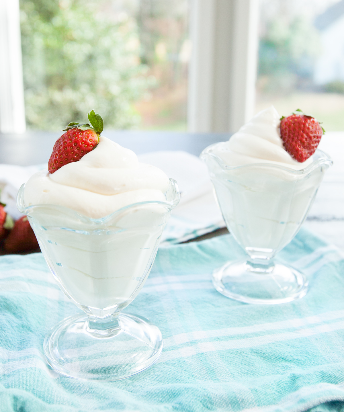 Two glass dishes swirled with cream cheese mousse and garnished with a strawberry.