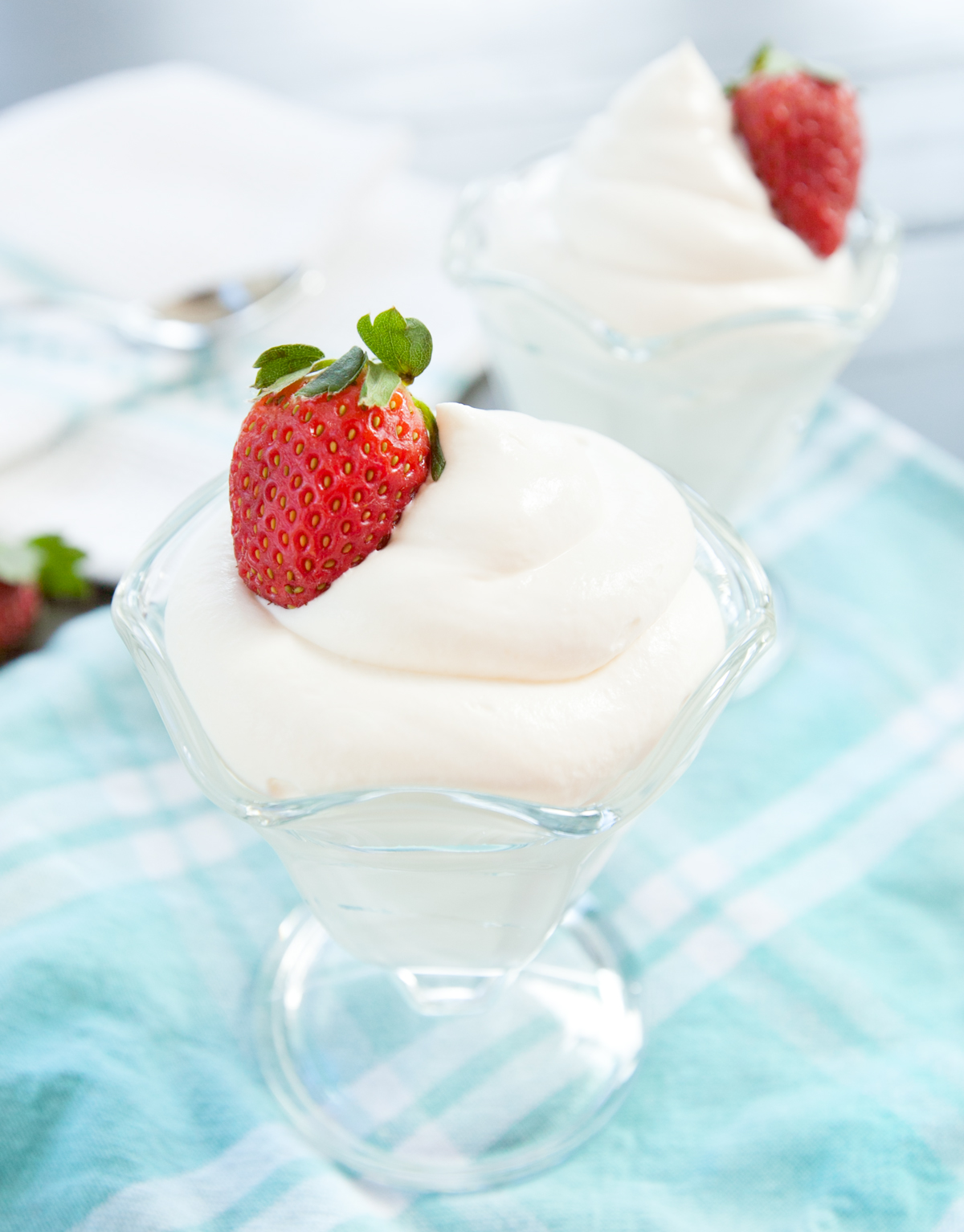 An old-fashioned ice cream dish filled with pillows of cream cheese mousse, garnished with a fresh strawberry.