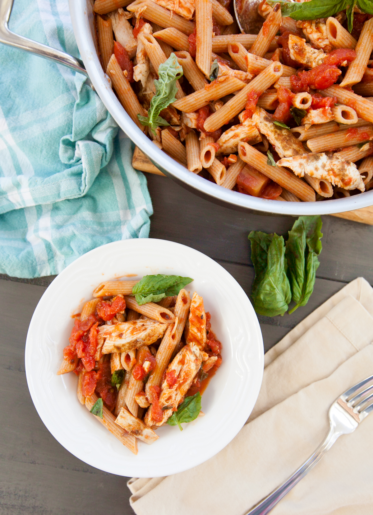 An overhead view of a completed spicy chicken pasta recipe with the saute pan and finished plated dish visible.