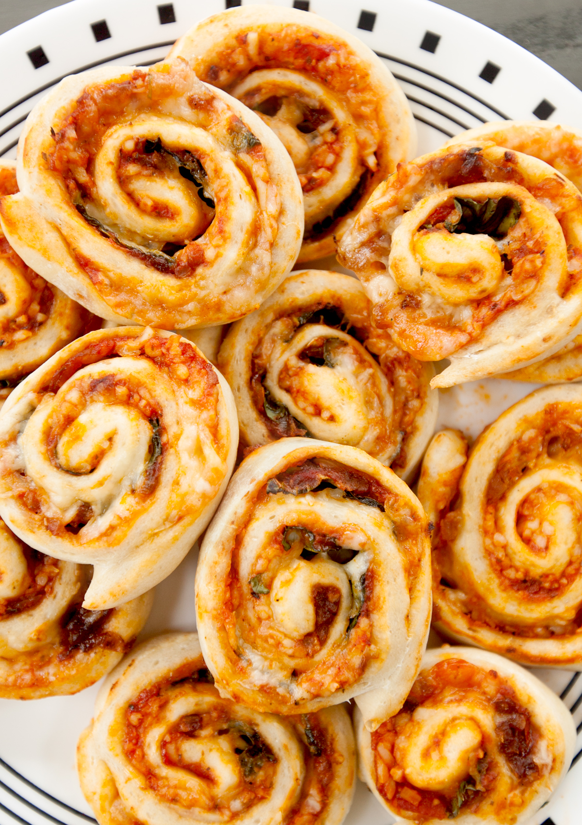 overhead view of a plate of vegetarian pizza rolls stuffed with sauce, cheese, onion, and fresh basil