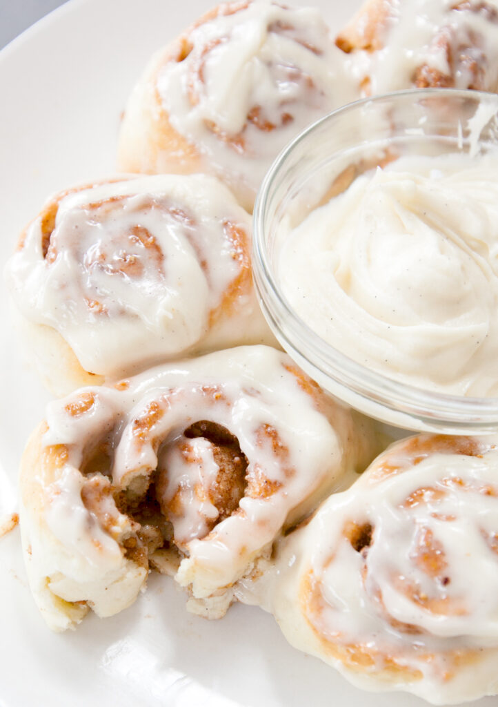 Air fryer cinnamon rolls covered in frosting with one torn apart to see the sweet insides.