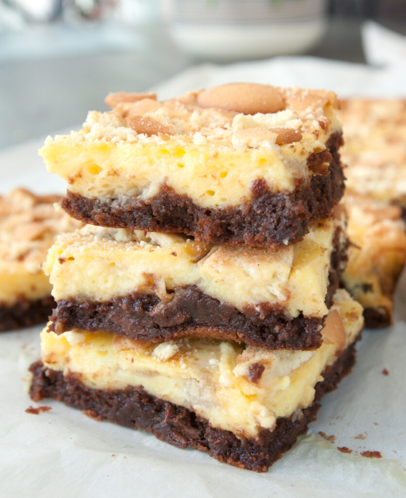 A stack of chocolatey banana puddng brownies with vanilla wafers on top. 