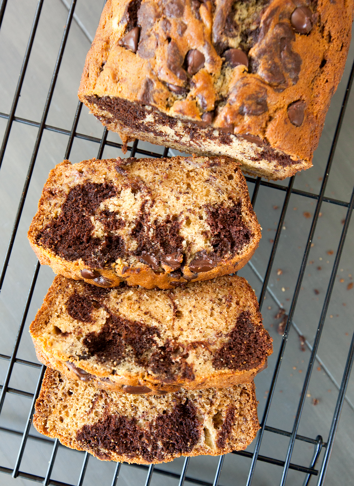 An overhead photo of chocolate swirled banana bread with slices visible and big chocolate chips on top.