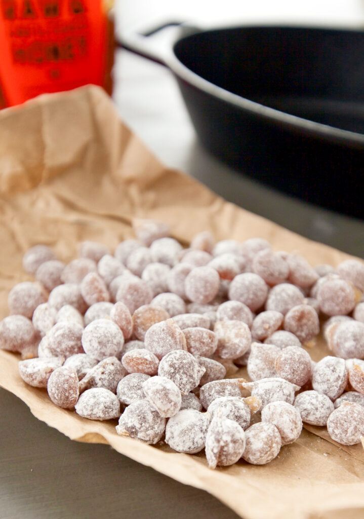 Close up photo of honey hard candy covered with powdered sugar, sitting on brown paper.