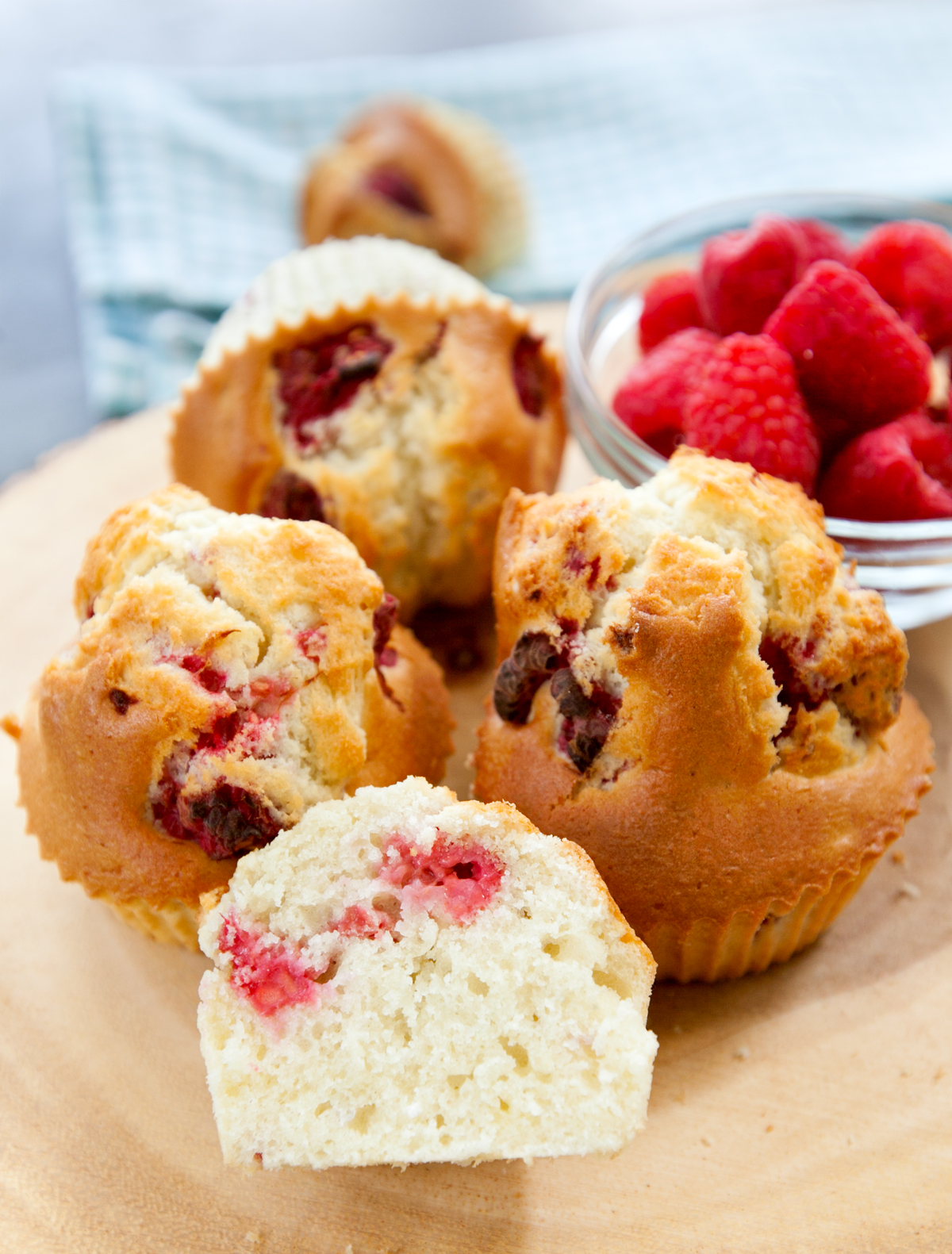 A muffins in air fryer recipe photo with one sliced open to show the tender crumb and chunks of raspberries.