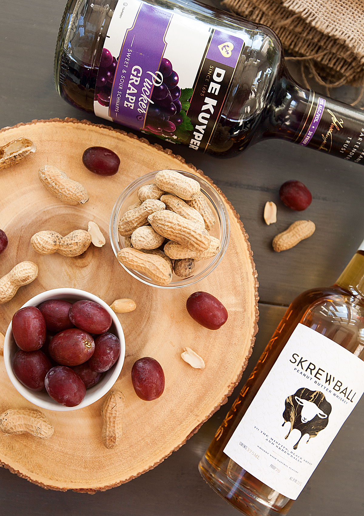 Overheard board with peanut butter whiskey, grape schnapps, whole grapes, and peanuts in the shell.