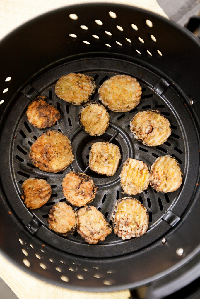 Fried pickles arranged in an air fryer, ready for reheating.