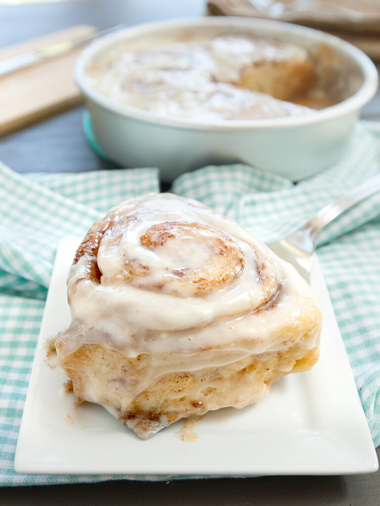 A photo of tik tok cinnamon rolls with one plated on a blue and white napkin.