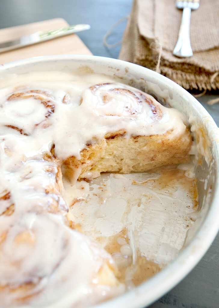 Close up view of a pan of tik tok cinnamon rolls with one removed.