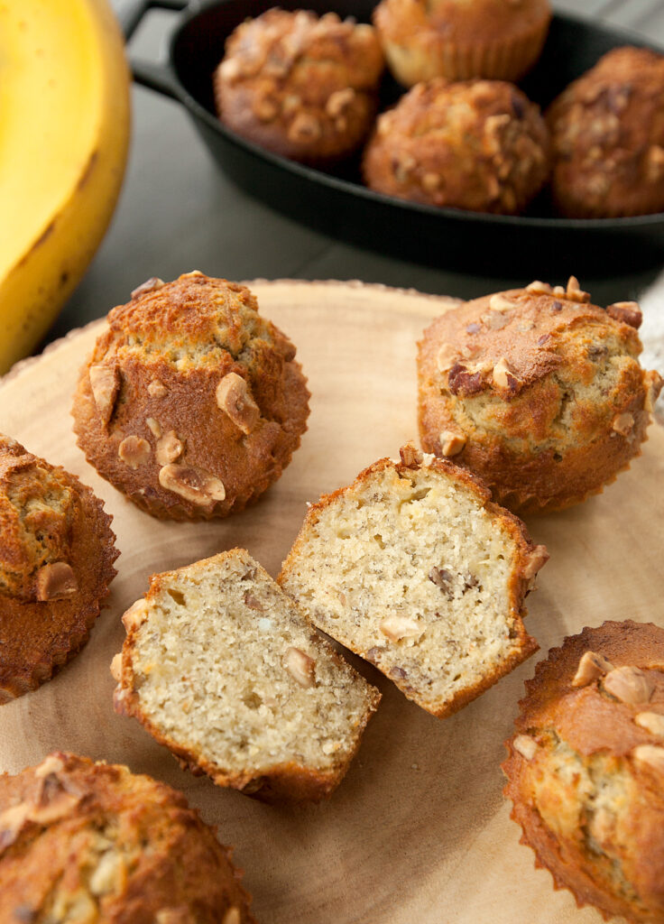 Overhead view of air fryer banana muffins with one sliced open to see the tender and nutty interior.