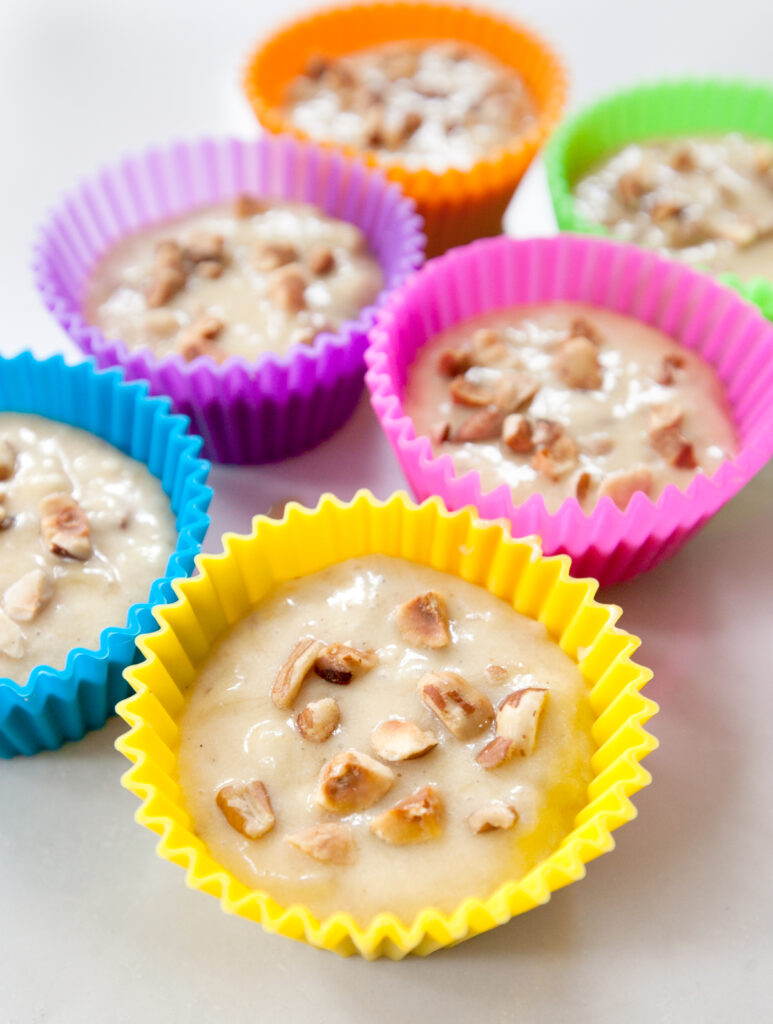 Colorful silicone baking cups holding banana muffing batter.