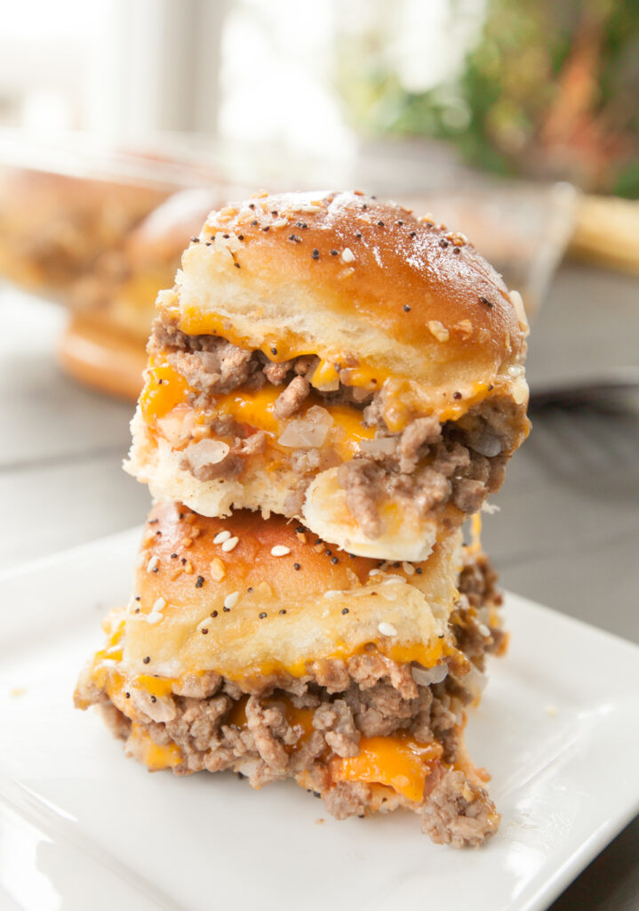 Two cheeseburger sliders with hawaiian rolls stacked on top of each other.