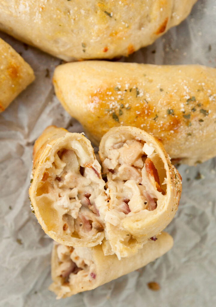 A chicken bacon ranch calzone cut open and facing the camera so the ingredients inside are visible.