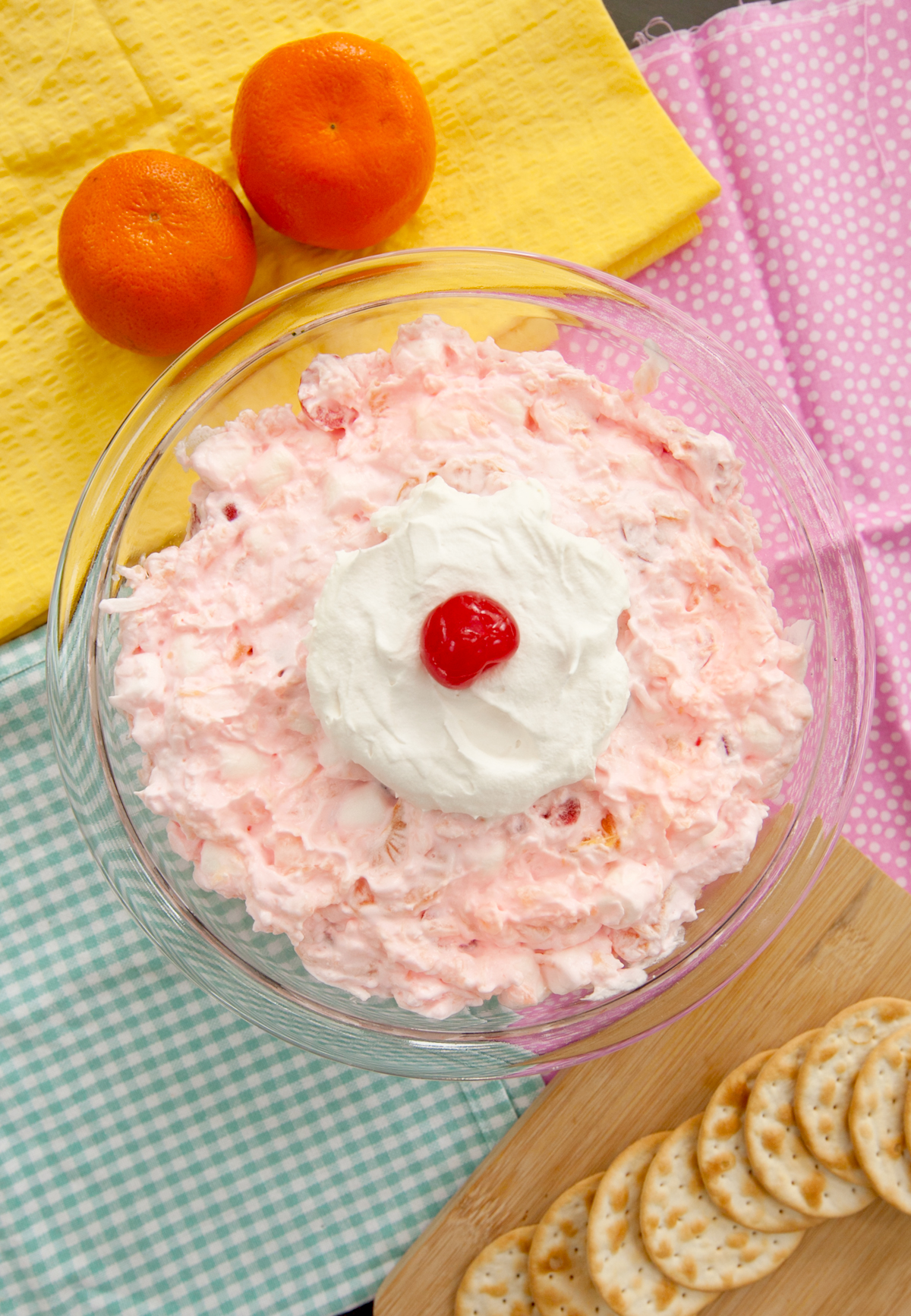 Overhead view of a glass dish of pink ambrosia salad, garnished with a cherry, that looks like the one shown in the movie Edward Scissorhands.