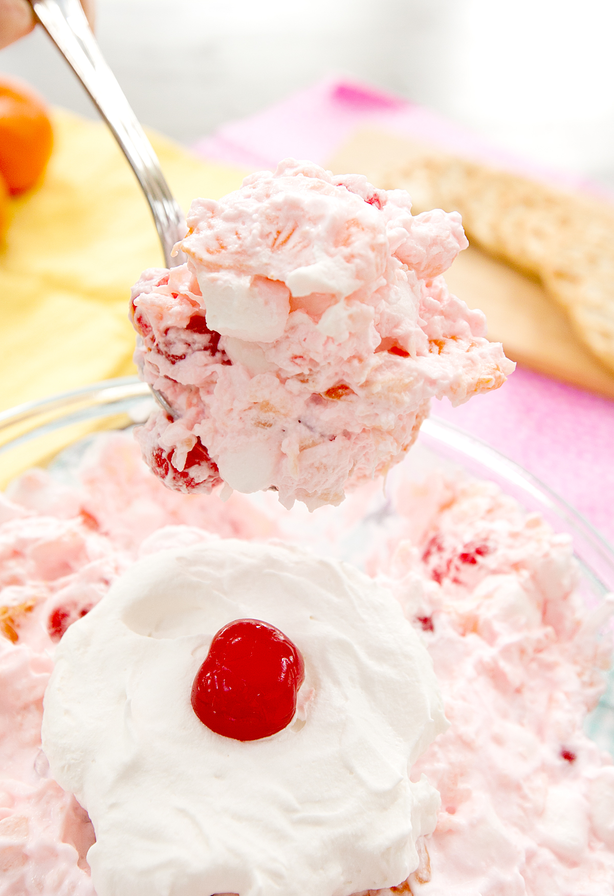 A massive spoonful of Ambrosia salad being lifted from the serving dish.