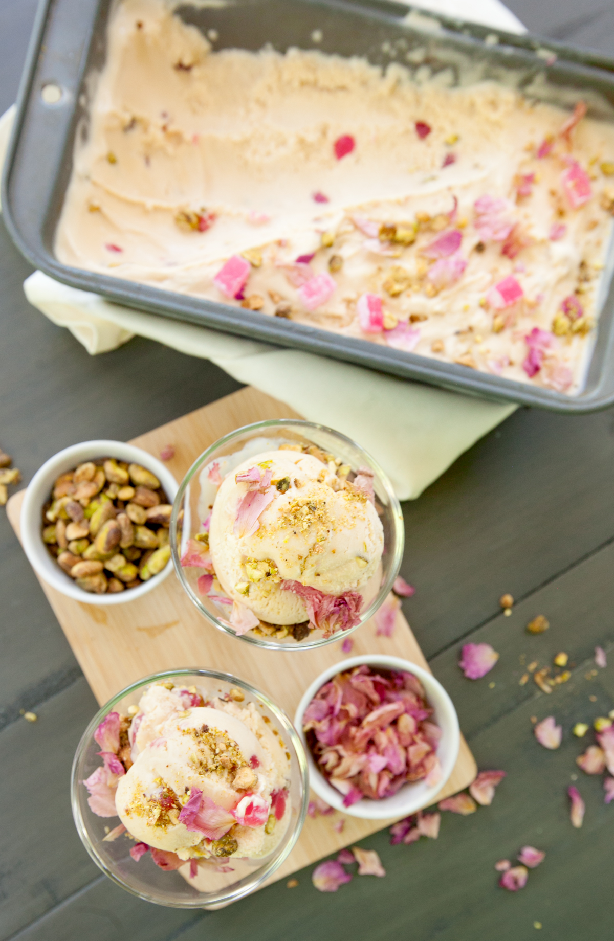 Overhead view of two dishes of rose-flavored ice cream filled with turkish delight, pistachios, and rose petals.