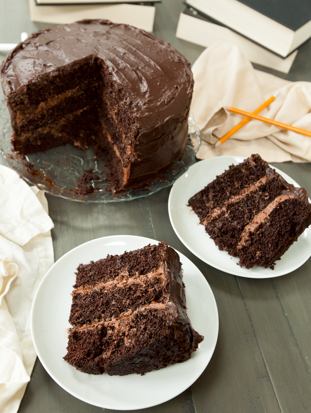 triple layer Matilda chocolate cake with two big slices cut out and placed on white plates.