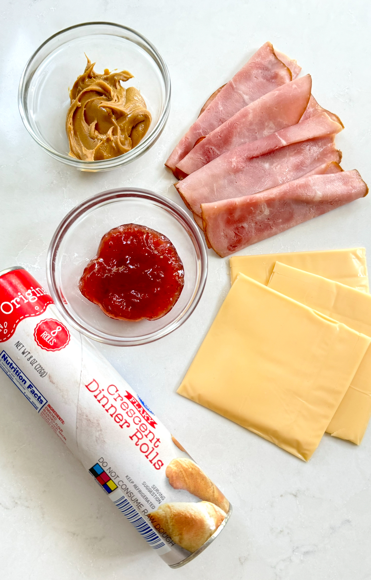 an overhead shot of a roll of crescent dough with peanut butter, jelly, ham, and cheese.
